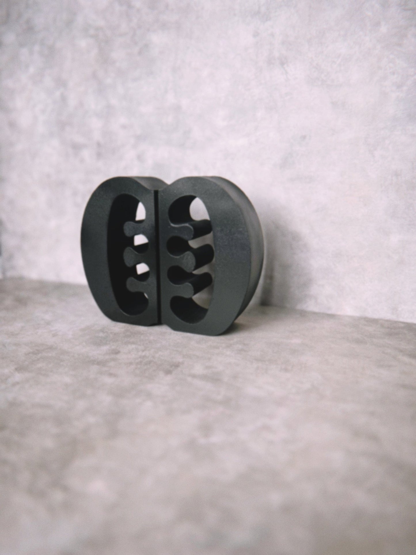 Decorative black Ese Ne Tekrema adinkra bookends on a light gray lime wash background.