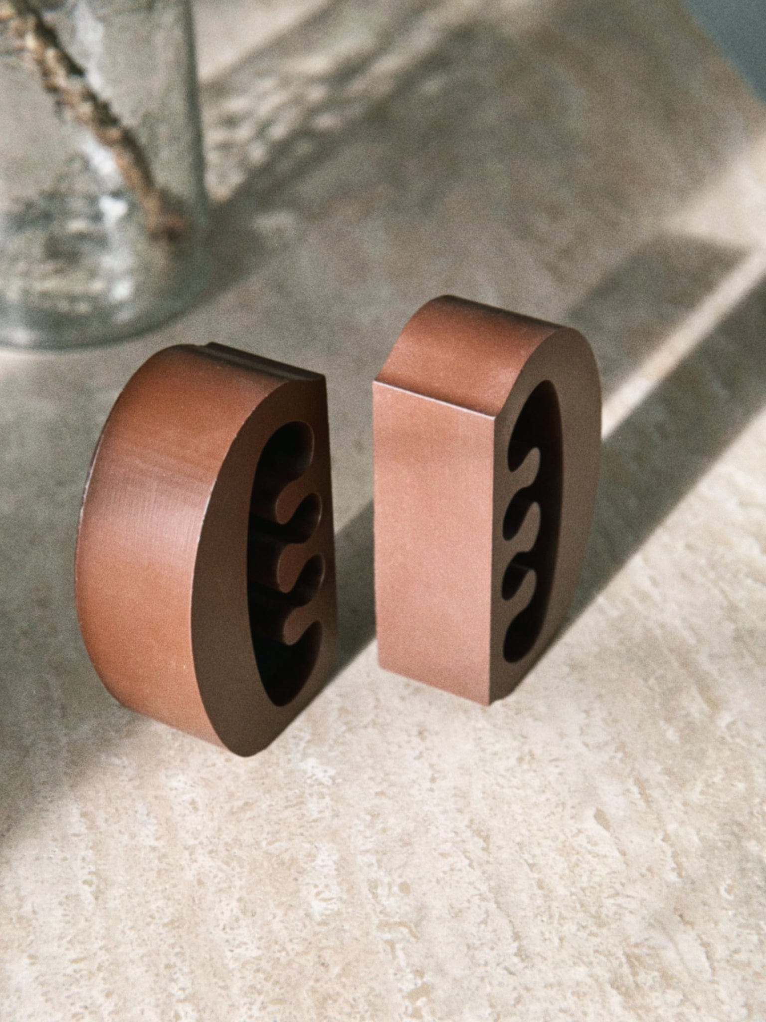Decorative coffee coloured Ese Ne Tekrema bookends on a marble table. 