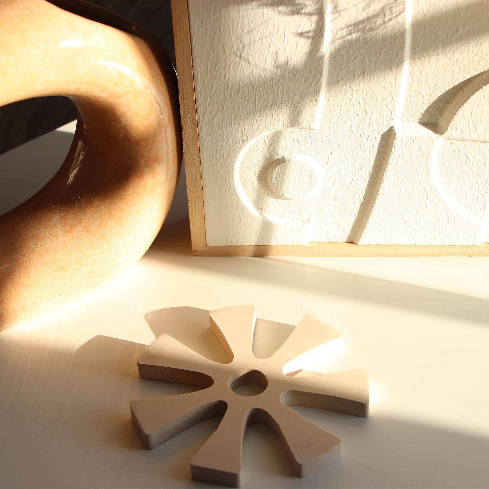 cream coloured Ananse Ntontan coaster on white background. 
